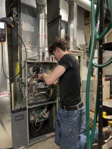 A skilled technician from Wright Mechanical servicing the internal components of a furnace in Ypsilanti, MI.