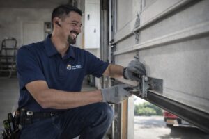 A Baystate Garage Door technician servicing a garage door roller and track in Milton, MA.