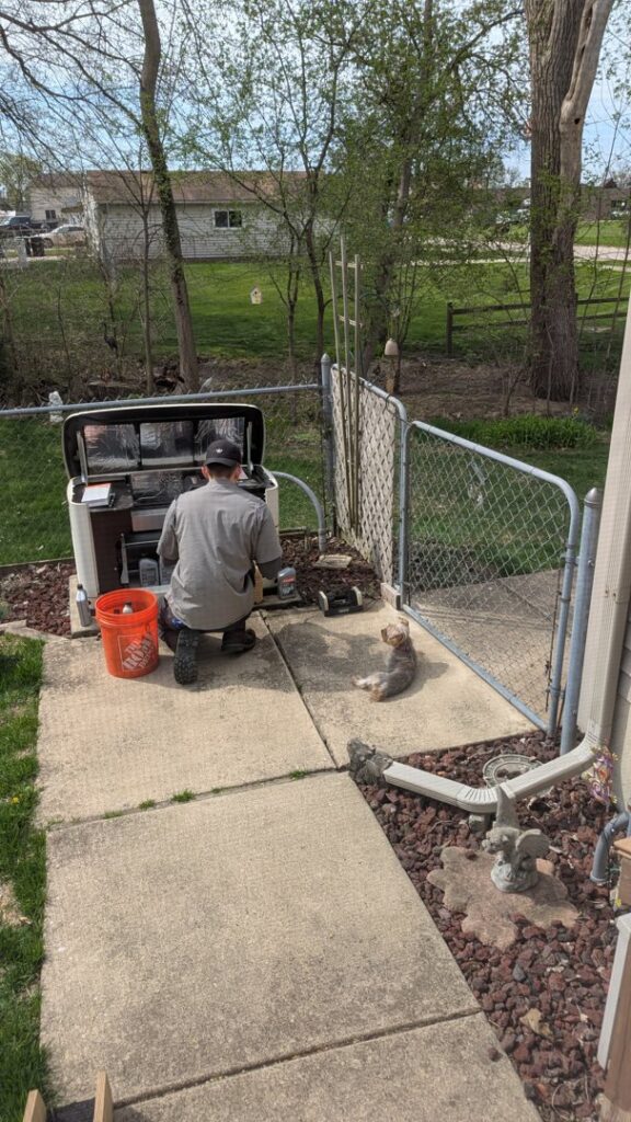 A Kelley Brothers LC technician servicing a Generac standby generator at a residential property in Livonia, MI.