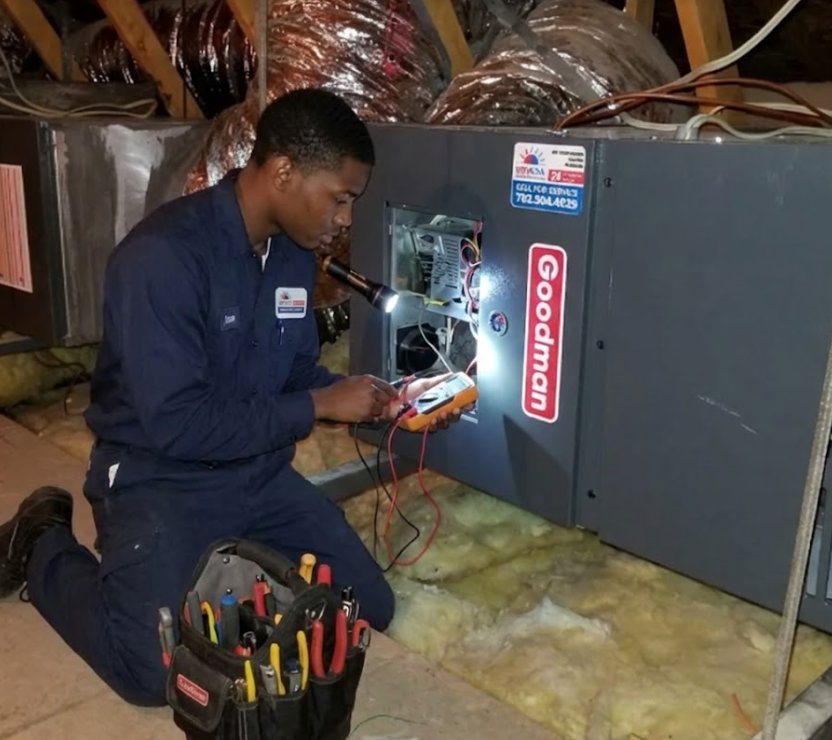 A technician servicing a Goodman HVAC unit in an attic with tools for RESTQ HVAC Repairs & Services in Rockville, MD.