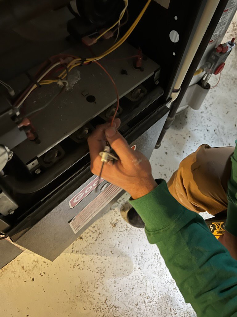 A TAS Mechanical Services technician servicing an HVAC furnace unit with a tool, performing maintenance in Kearney, MO.