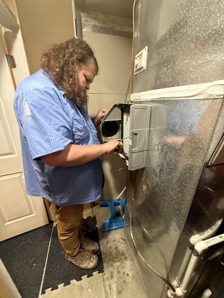 A technician servicing an HVAC humidifier or accessory attached to ductwork for Direct Service HVAC & Maintenance in Lewisburg, OH.
