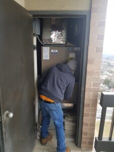 A technician from AVS Heating and Air Conditioning servicing an indoor HVAC unit in Alexandria, VA, demonstrating professional service.