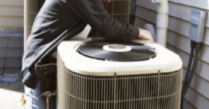 A technician performing maintenance on an outdoor HVAC condenser unit for Blanton & Son Heating and Cooling in Clayton, NC