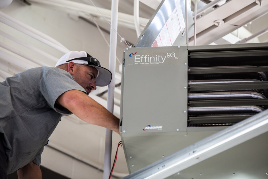 A skilled technician servicing an indoor commercial HVAC unit for S&S Mechanical in St. George, UT