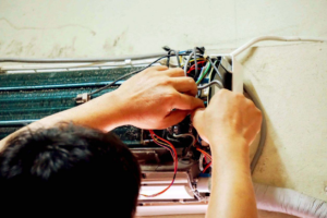 A technician servicing the internal components of an indoor AC unit for AC Phoenix LLC AC Repair & Service in Glendale, AZ.