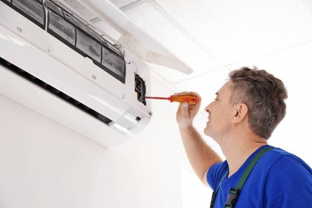 A technician servicing an indoor air conditioning unit with a screwdriver for Cool Concepts A/C & Heating in San Antonio, TX.