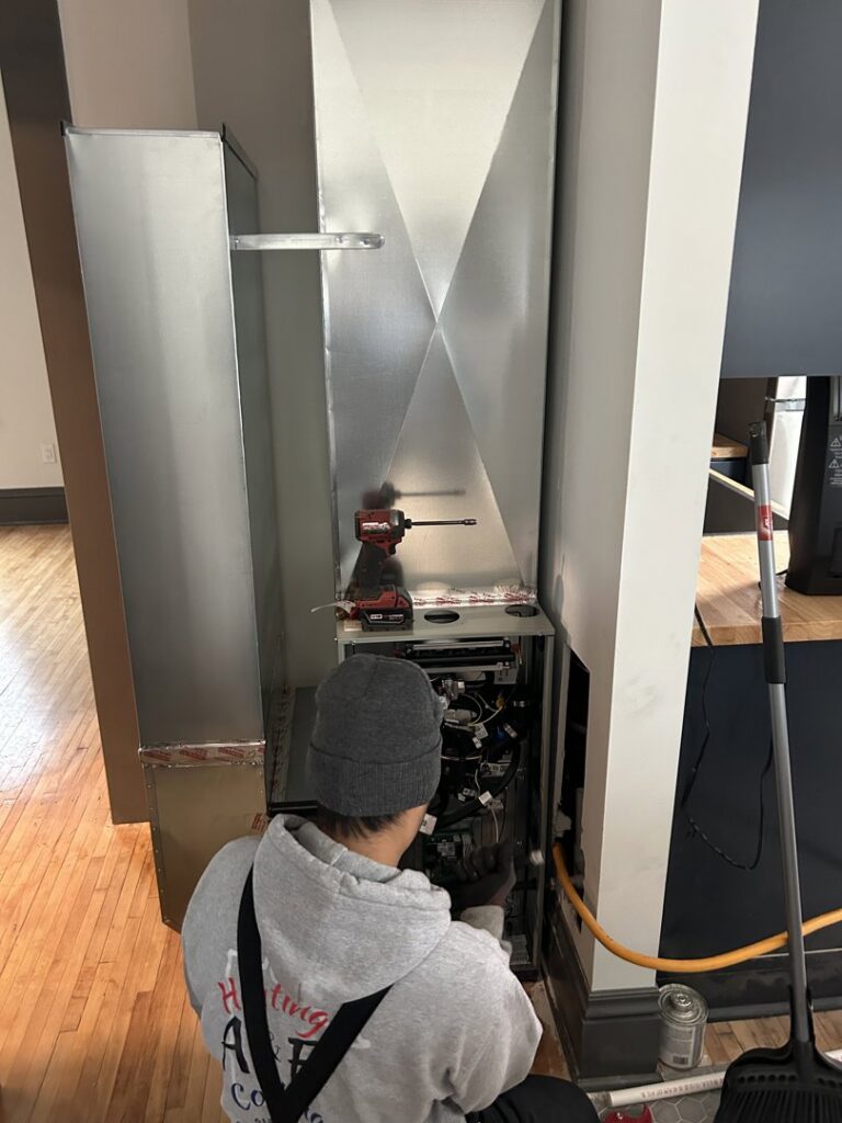 An A&E Heating & Cooling technician servicing an indoor HVAC unit and ductwork in Fort Worth, TX.