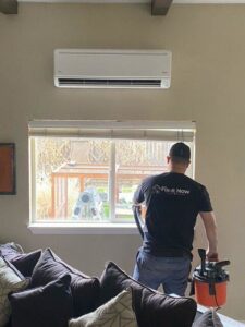 A Fix It Now Heating and Cooling technician servicing an indoor mini-split unit with a vacuum cleaner in Thornton, CO