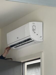 A technician servicing an indoor mini-split HVAC unit, demonstrating expertise from Blue Collar Mechanical LLC in Indianapolis, IN.