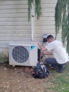A technician servicing an outdoor mini-split air conditioning unit for JJJ Techs Heating and Cooling in Kinzers, PA.