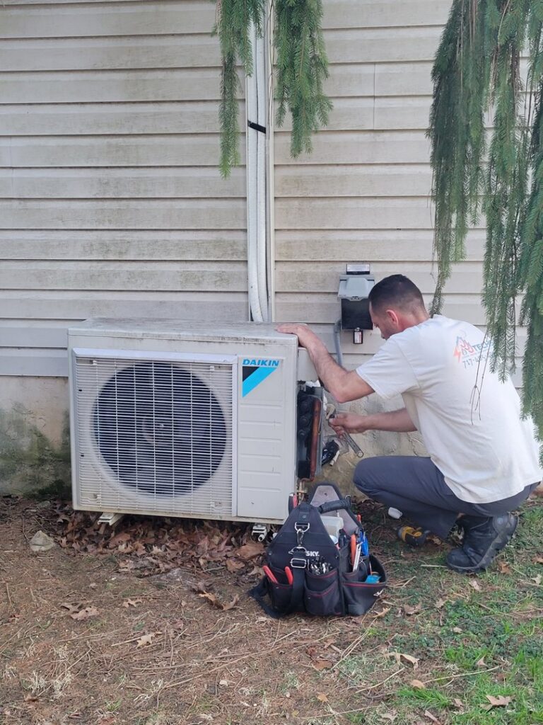 A technician servicing an outdoor mini-split air conditioning unit for JJJ Techs Heating and Cooling in Kinzers, PA.