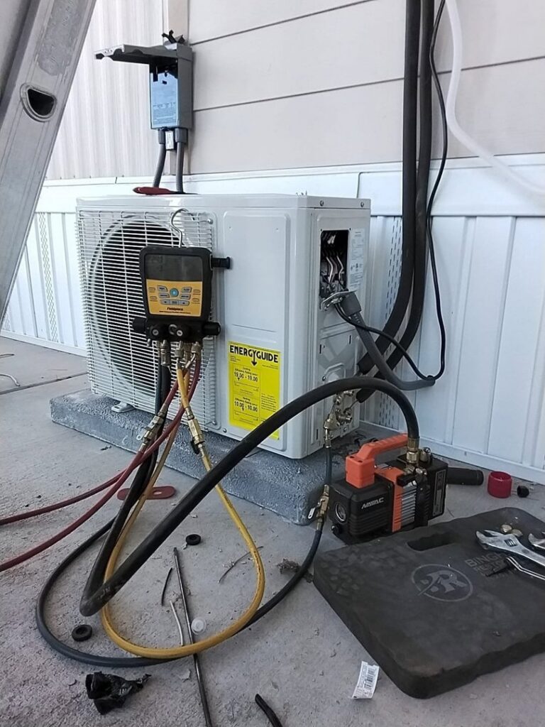 A technician servicing an outdoor mini-split HVAC unit with gauges and a vacuum pump for Heating & Air Paramedics - Tucson in Tucson, AZ.