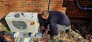 A technician servicing an outdoor Mitsubishi Electric mini-split condenser unit for ReDesign Air in Winchester, VA.