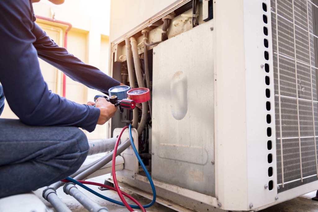 A technician from BTU Systems servicing an outdoor AC unit with gauges in Stamford, CT