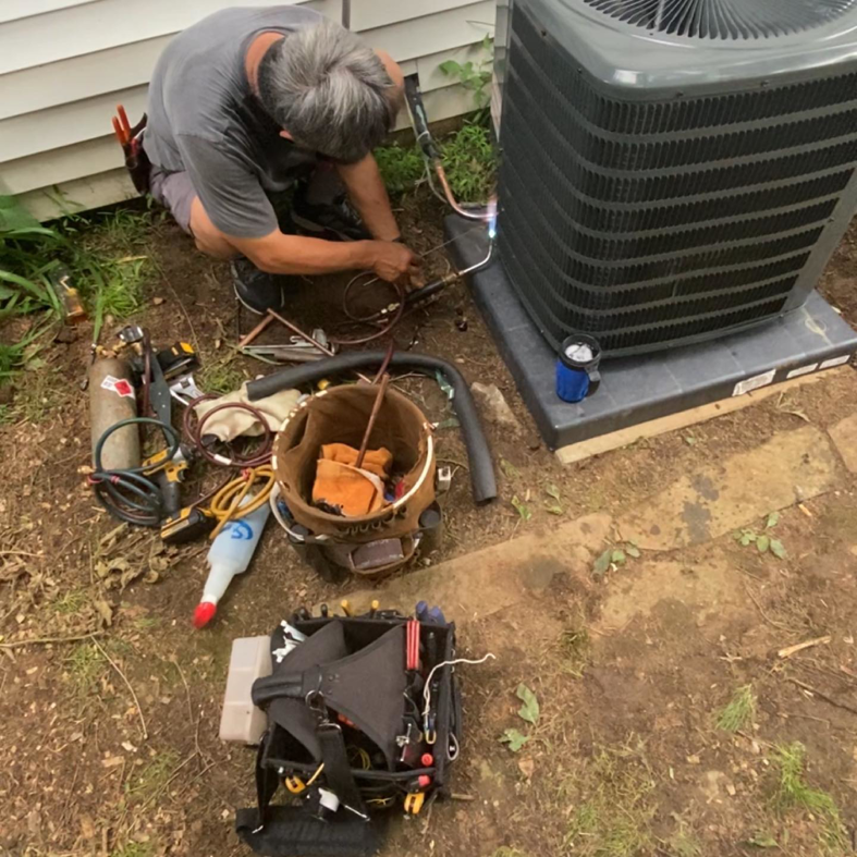 A technician servicing an outdoor air conditioning unit for Doctor Air HVAC in Philadelphia, PA.