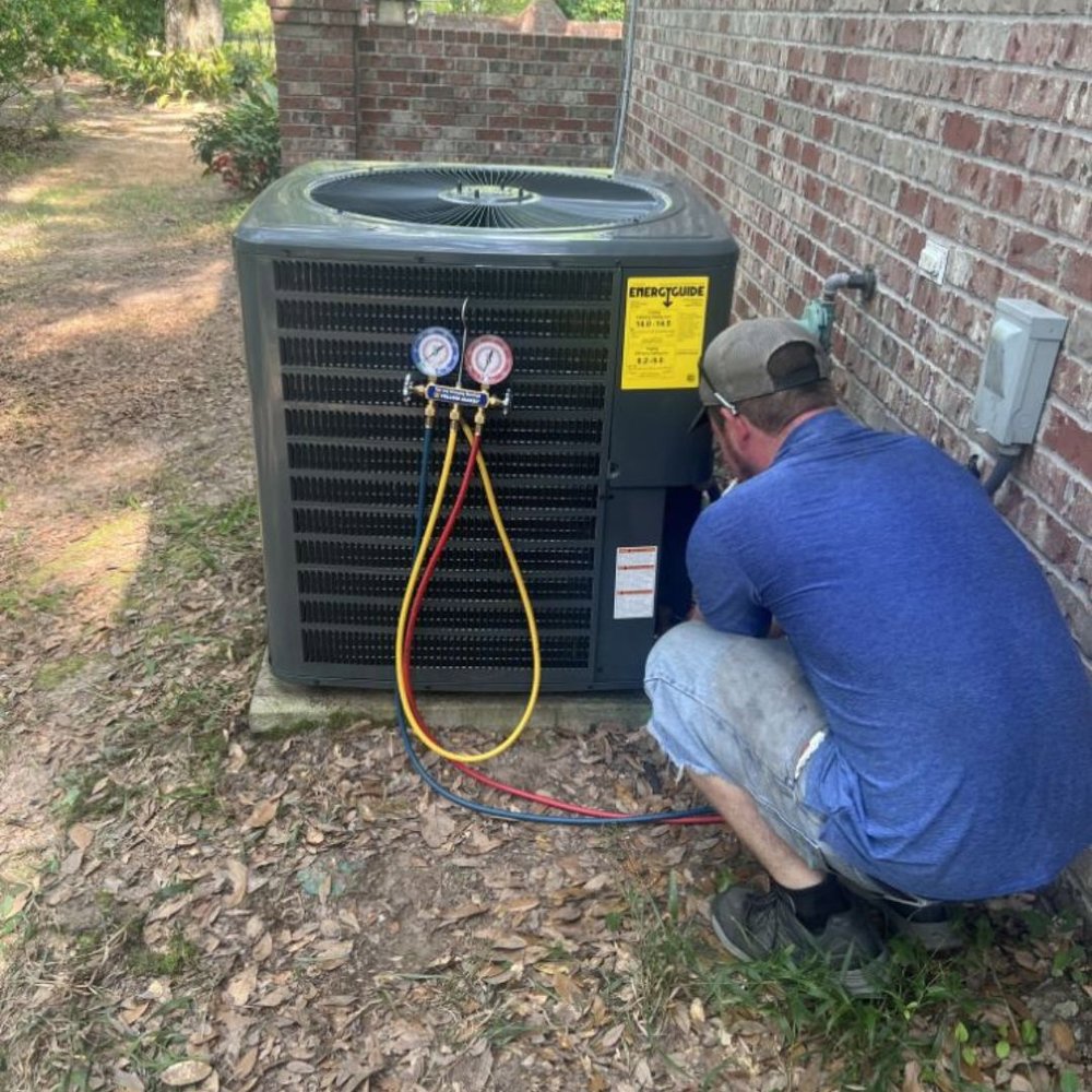 A technician from Dodson A/C & Appliance servicing an outdoor AC unit with gauges in Biloxi, MS.