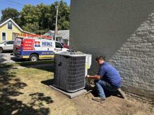 A technician servicing an outdoor air conditioning unit at a residential property for Heinz HVAC & Plumbing in Vincennes, IN.