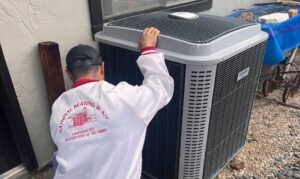 A National Heating & Cooling Company technician servicing an outdoor air conditioning unit in Lakewood, CO.