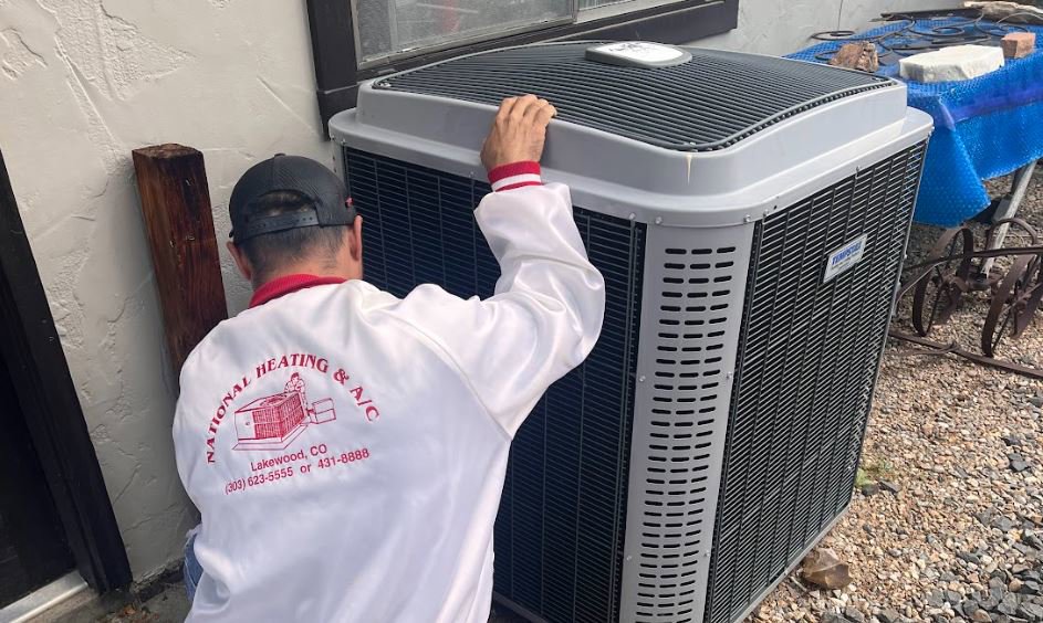 A National Heating & Cooling Company technician servicing an outdoor air conditioning unit in Lakewood, CO.
