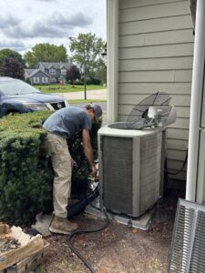 A technician from Nordic Air Heating & Cooling servicing an outdoor air conditioning unit in West Allis, WI.