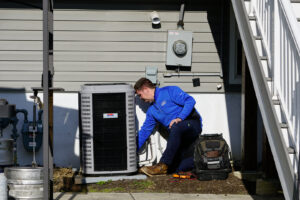 A SANKS Mechanical technician kneeling to service an outdoor air conditioning unit at a residential property in Philadelphia, PA.