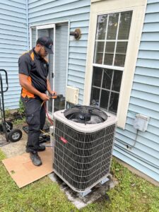 A technician servicing an outdoor AC unit, connecting gauges for diagnostic work by Simply Home Service in Gaithersburg, MD.