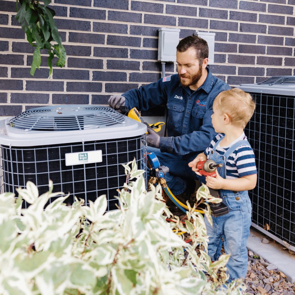 A technician servicing an outdoor AC unit with a child observing at Utah Mechanical Heating and Air Conditioning in South Ogden, UT.