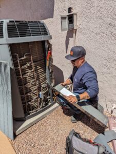 A technician servicing an outdoor HVAC condenser unit with exposed coils for maintenance by Blue Collar Mechanical LLC in Indianapolis, IN.