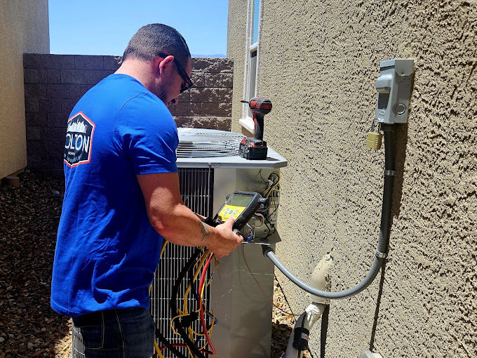 A technician servicing an outdoor HVAC unit with diagnostic tools for Colton Air Conditioning - Las Vegas in Las Vegas, NV.