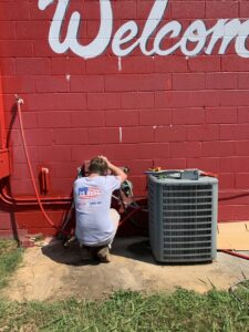 A U.S. HVAC Services technician performing maintenance on an outdoor HVAC unit in Madison, AL.