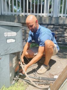 A technician from Davis Heating, Air Conditioning & Home performing service on a residential outdoor AC unit in Overland Park, KS.