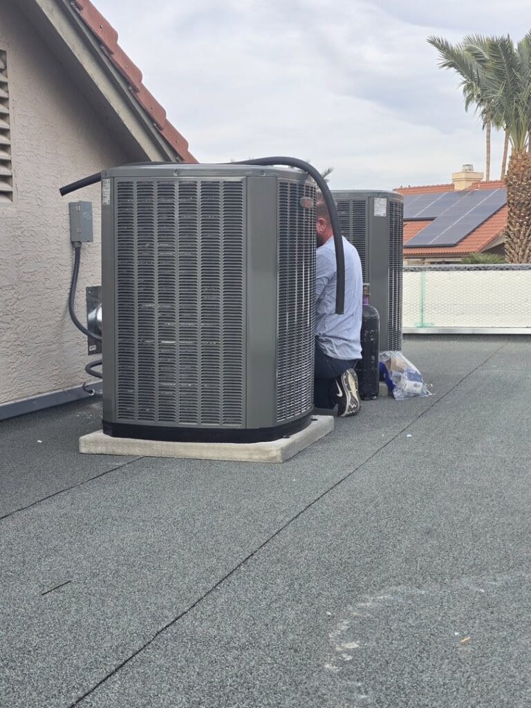 A technician servicing two outdoor AC condenser units on a rooftop for Az AC and Heat Services in Queen Creek, AZ.