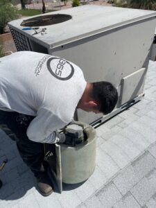 A technician servicing the blower motor assembly of a rooftop HVAC unit for 365 Mechanical in Mesa, AZ.