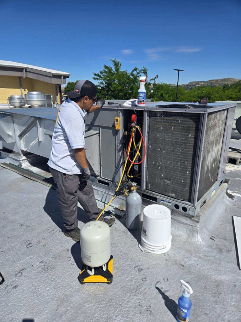 HVAC technician servicing a large commercial rooftop unit for HVAC Ministries LLC in Salem, OR