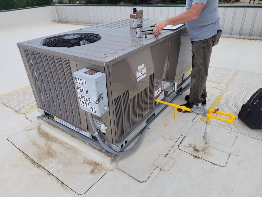 A technician from Kraemer Mechanical servicing a commercial rooftop HVAC unit in Broomfield, CO.