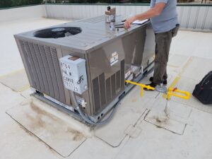 A technician from Kraemer Mechanical servicing a commercial rooftop HVAC unit in Broomfield, CO.