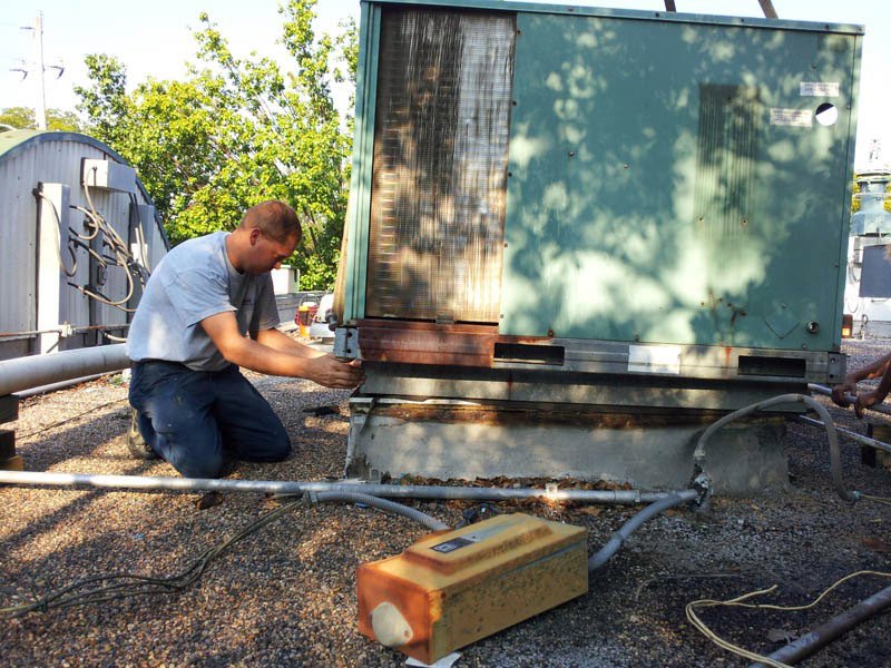 An Air Care Heating and Cooling Services technician servicing a large commercial rooftop HVAC unit in Shreveport, LA.