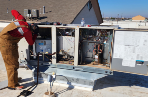 A skilled technician servicing a commercial rooftop HVAC unit for Air Factory Heating & Cooling Company in Oklahoma City, OK.