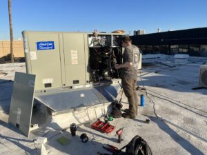 A technician performing maintenance on the internal components of a large rooftop HVAC unit for Blue Collar Mechanical LLC in Indianapolis, IN.
