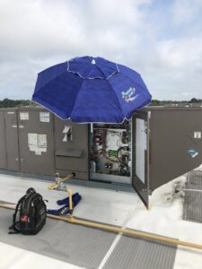 A technician's backpack next to an open commercial rooftop HVAC unit being serviced by DND Mechanical in Columbus, OH.