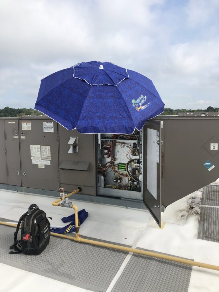 A technician's backpack next to an open commercial rooftop HVAC unit being serviced by DND Mechanical in Columbus, OH.