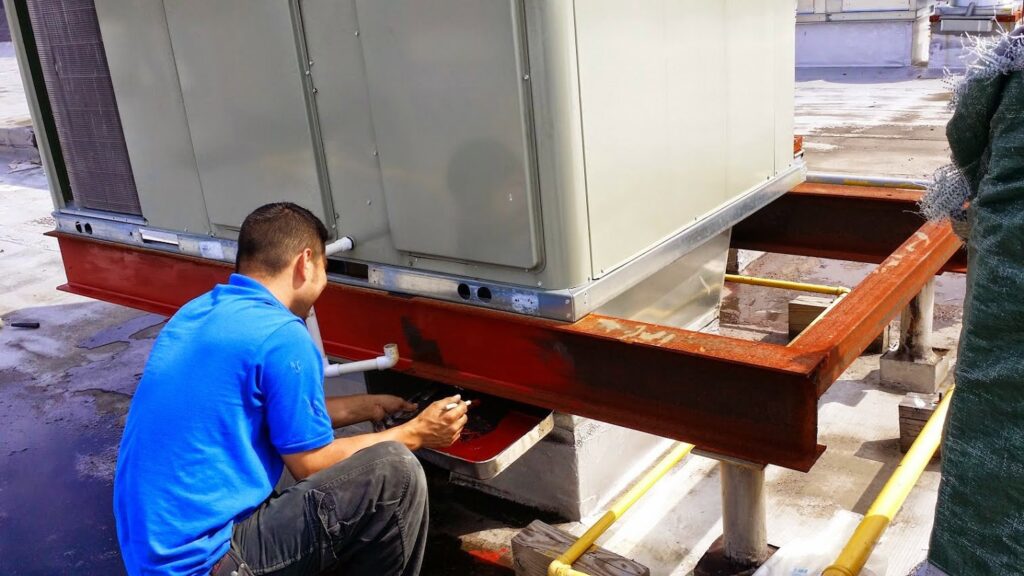 A technician servicing a large commercial rooftop HVAC unit for Enviromax Heating & Cooling in Peekskill, NY.