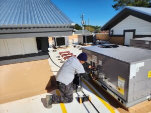 An HVAC technician servicing a commercial rooftop heating and cooling unit for HP Mechanical LLC in Santa Rosa, CA.