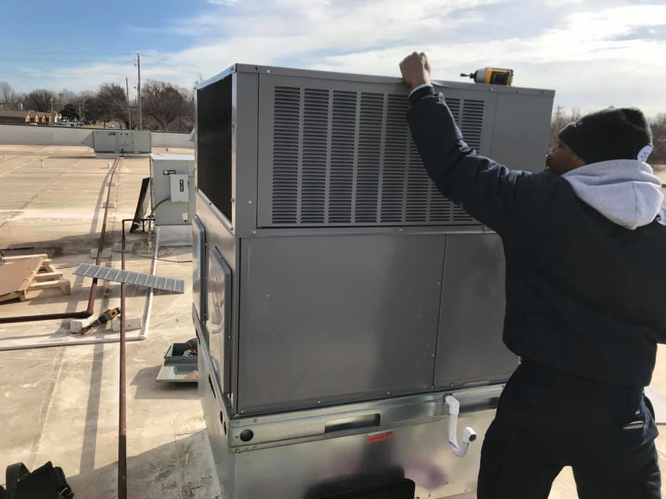 A technician from Prudhom Mechanical LLC servicing a commercial rooftop HVAC unit in Edmond, OK
