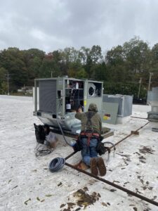 A PureAir HVAC technician servicing a large commercial rooftop HVAC unit in Bel Air, MD.