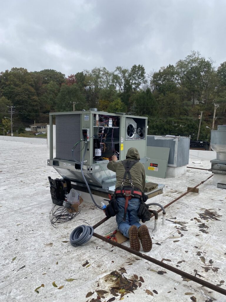 A PureAir HVAC technician servicing a large commercial rooftop HVAC unit in Bel Air, MD.