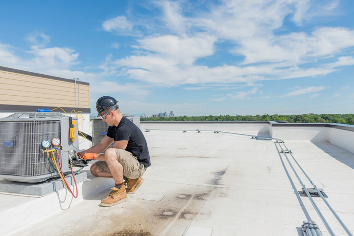 A technician servicing a commercial rooftop HVAC unit under a clear sky for Setpoint Refrigeration LLC in Liberty Hill, TX