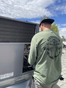 A Steadfast Mechanical technician servicing a rooftop HVAC unit under a blue sky in Gilbert, AZ.