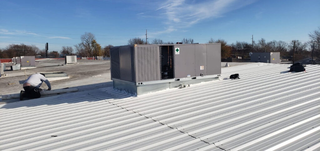 A Tornado Heating and Air technician servicing a commercial rooftop HVAC unit in Tulsa, OK.